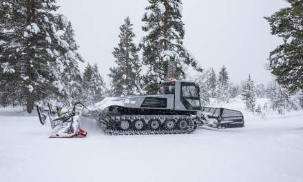 A snow groomer passing and turning